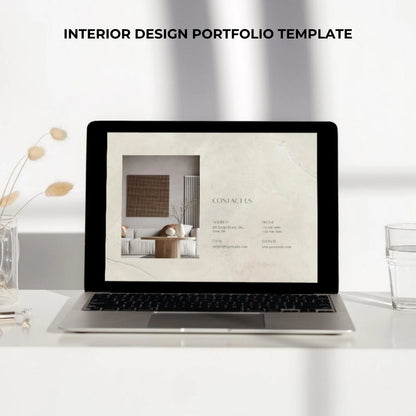 Laptop displaying an interior design portfolio on a white desk with decor items.
