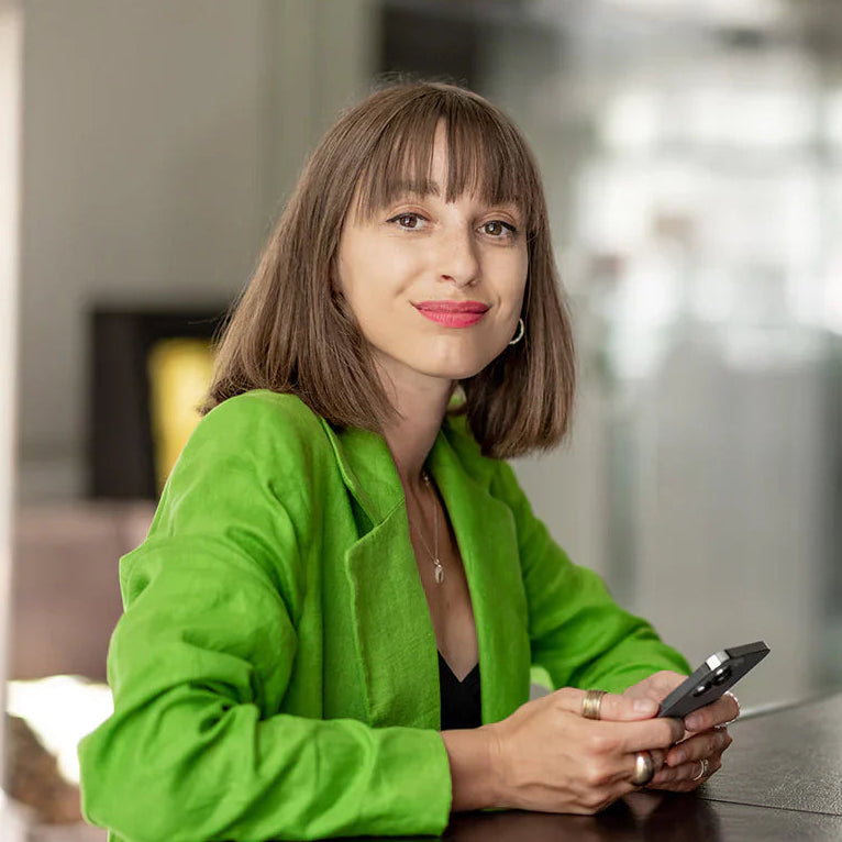 Interior designer in a green jacket holding a phone in an indoor setting