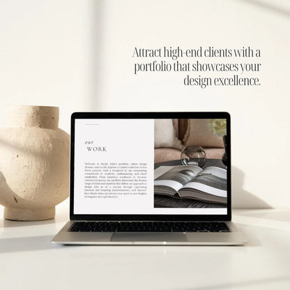 Laptop on a table with a screen displaying 'our work' text, next to a vase.