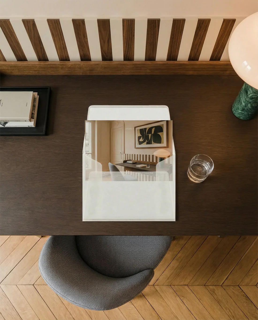 Clear acrylic box on a wooden table with a glass of water and a lamp in a room setting.