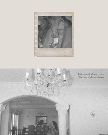 Chandelier in a room with a mirror and a photo of jewelry in a frame.