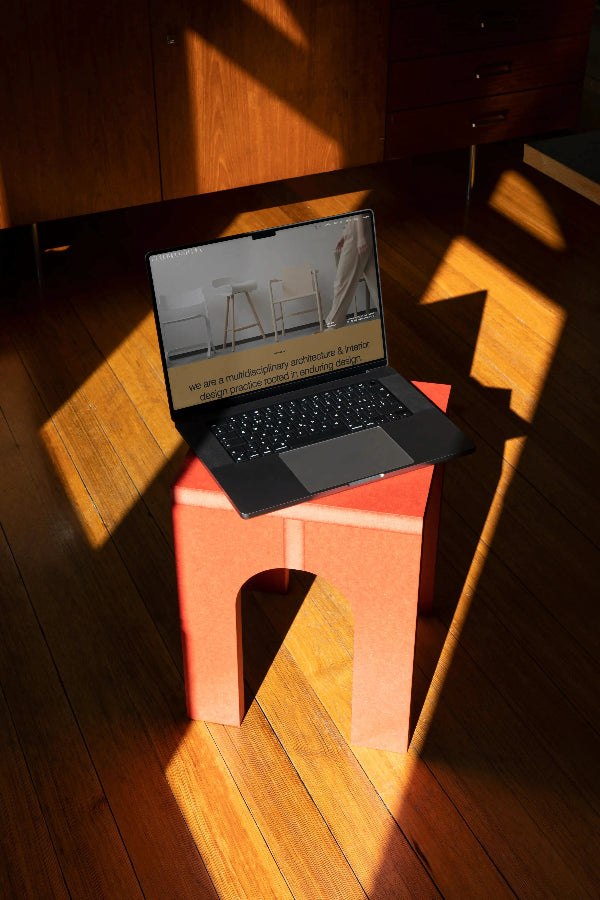 Laptop on a red stool with a wooden floor background