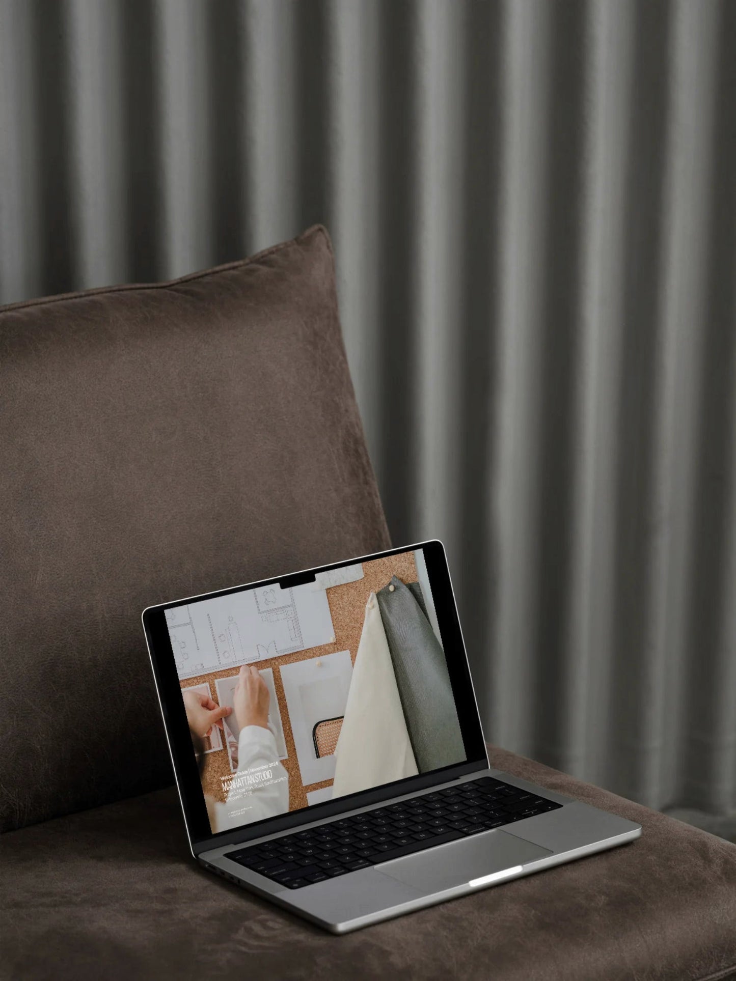 Laptop on a brown cushion with a curtain in the background